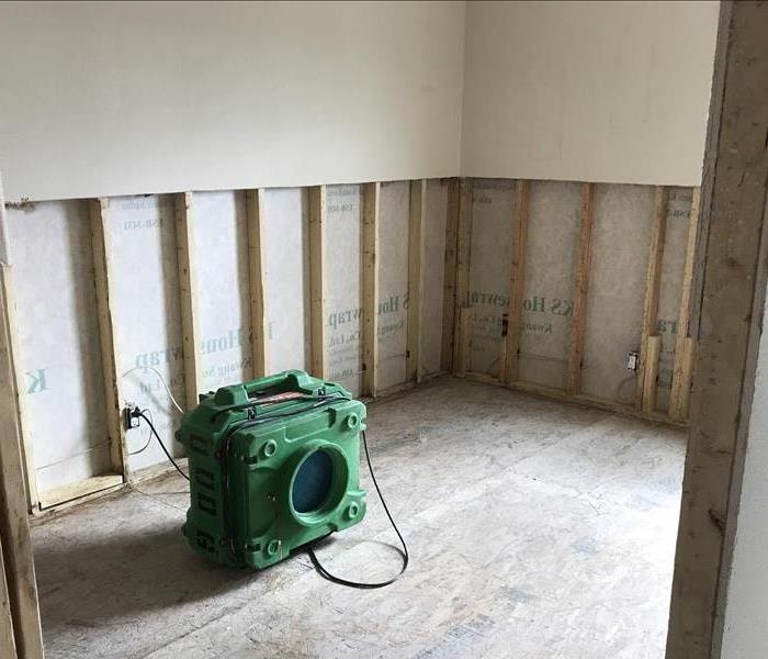 Removed wall and flooring with green equipment on floor.